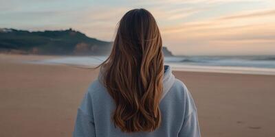 Woman gazing at ocean during sunset on a serene beach photo
