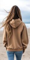 Woman walks along sandy beach wearing a casual hoodie and jeans photo