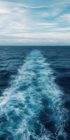 Ocean waves create a beautiful trail behind a moving vessel photo