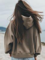 Woman with long hair wearing hoodie on beach at sunset photo