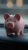 A cute pink piggy bank sits on the dashboard of a car during daytime photo
