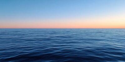 Calming blue ocean waves under a pastel sunset sky at dusk photo