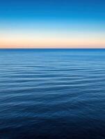 Tranquil sunset over calm ocean waters during twilight hours photo