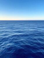 Calm blue ocean under clear sky at sunset during summer photo