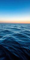 Calm ocean waves at sunset with a clear sky above the horizon photo