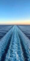 A serene view of ocean waves at sunset from a moving ship photo