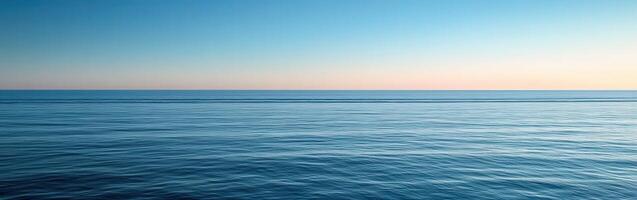 Calm ocean horizon at dusk with gentle waves and clear sky photo