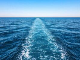 Calm blue ocean waves and wake trail from a boat on a sunny day photo
