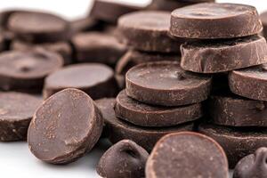 Tempting dark chocolate discs stacked on a white background photo
