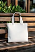 A white tote bag resting on a wooden bench in a sunny outdoor setting photo