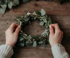 Making a natural wreath with foliage and herbs on a wooden table photo