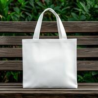 Simple white tote bag displayed on a wooden bench in a garden setting photo