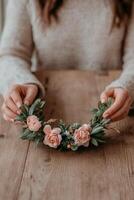 Woman creating a floral wreath using pink flowers and greenery indoors photo