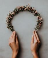 Delicate hands holding a floral wreath on a soft gray background photo