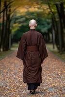 Buddhist monk walking along a serene autumn path in a tranquil forest photo