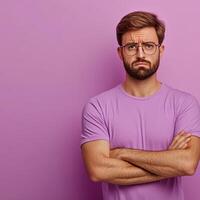 A sad man with crossed arms standing against a purple background photo