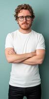 A sad man stands with crossed arms against a plain teal background photo