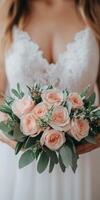 A bride holds a delicate bouquet of pink roses in a soft dress photo