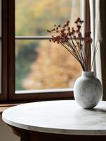 Elegant vase with dried flowers on a marble table beside a window photo
