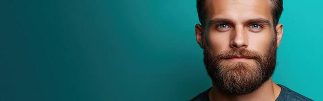 Young man with a well-groomed beard poses against a vibrant backdrop photo