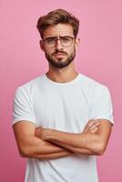 Sad man with crossed arms poses against a vibrant pink background photo