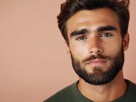 Young man with a stylish beard posing against a pink background photo