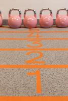 Pink kettlebells stand on a track with markings photo