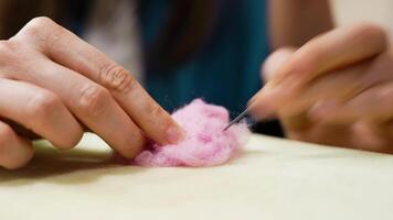 Creating soft pink wool crafts with needle felting techniques at a workshop video