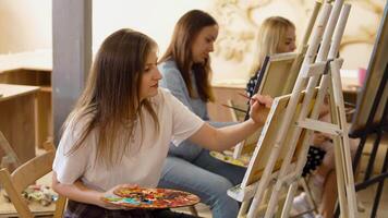 Art workshop in a bright studio with participants painting on easels video