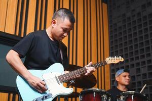 Man playing electric guitar and practicing with friend in home studio photo