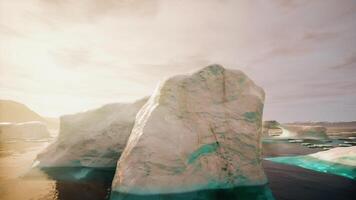 A large iceberg floating in the ocean next to a beach video