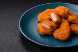 Delicious fresh crispy chicken nuggets on a dark concrete background photo