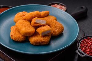 Delicious fresh crispy chicken nuggets on a dark concrete background photo