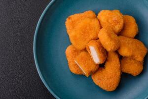 Delicious fresh crispy chicken nuggets on a dark concrete background photo