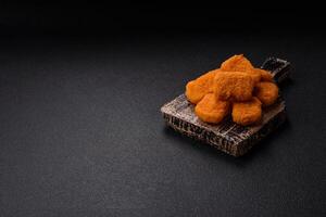 Delicious fresh crispy chicken nuggets on a dark concrete background photo