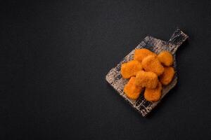 Delicious fresh crispy chicken nuggets on a dark concrete background photo