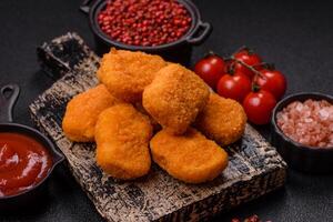 Delicious fresh crispy chicken nuggets on a dark concrete background photo