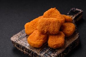 Delicious fresh crispy chicken nuggets on a dark concrete background photo