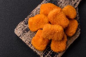 Delicious fresh crispy chicken nuggets on a dark concrete background photo