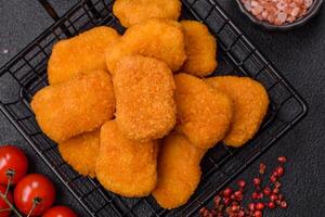 Delicious fresh crispy chicken nuggets on a dark concrete background photo