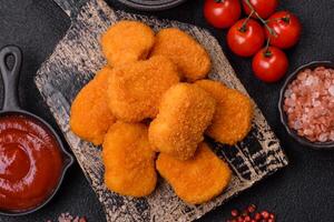 Delicious fresh crispy chicken nuggets on a dark concrete background photo