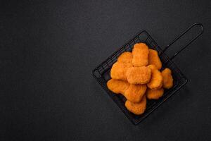 Delicious fresh crispy chicken nuggets on a dark concrete background photo