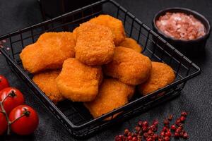 Delicious fresh crispy chicken nuggets on a dark concrete background photo