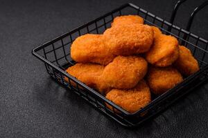 Delicious fresh crispy chicken nuggets on a dark concrete background photo