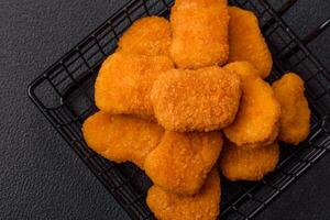 Delicious fresh crispy chicken nuggets on a dark concrete background photo