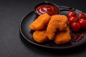 Delicious fresh crispy chicken nuggets on a dark concrete background photo