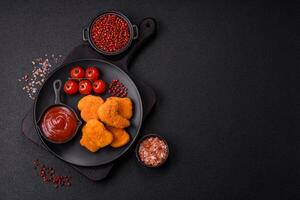 Delicious fresh crispy chicken nuggets on a dark concrete background photo