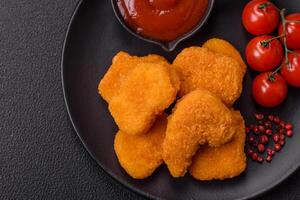 Delicious fresh crispy chicken nuggets on a dark concrete background photo
