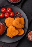Delicious fresh crispy chicken nuggets on a dark concrete background photo
