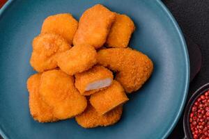 Delicious fresh crispy chicken nuggets on a dark concrete background photo